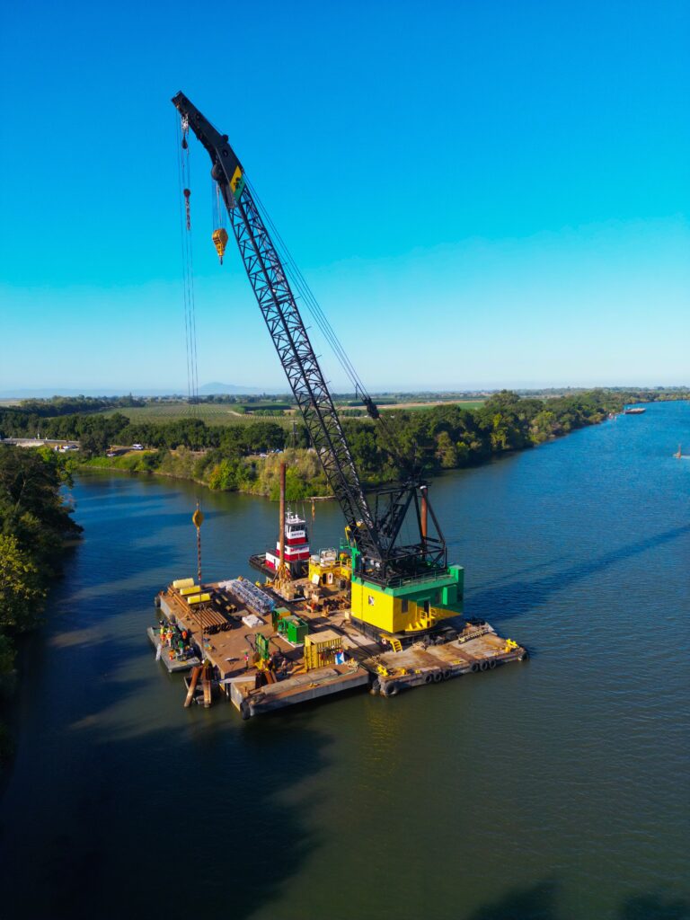 A crane operating on a floating platform in a river.