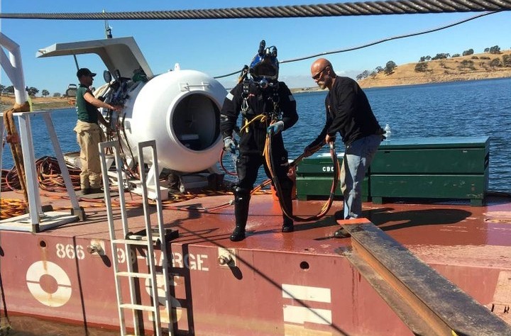 A diver in full gear preparing to enter the water from a boat.