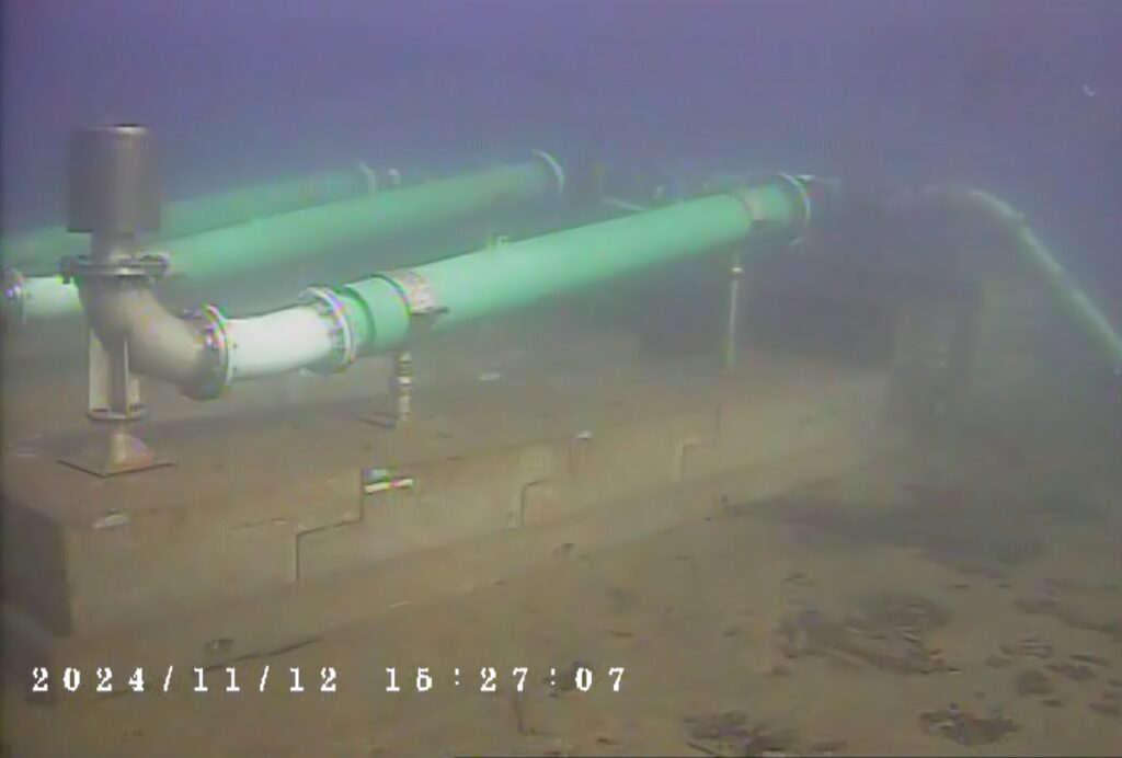 Underwater view of a submarine or torpedo on the ocean floor.